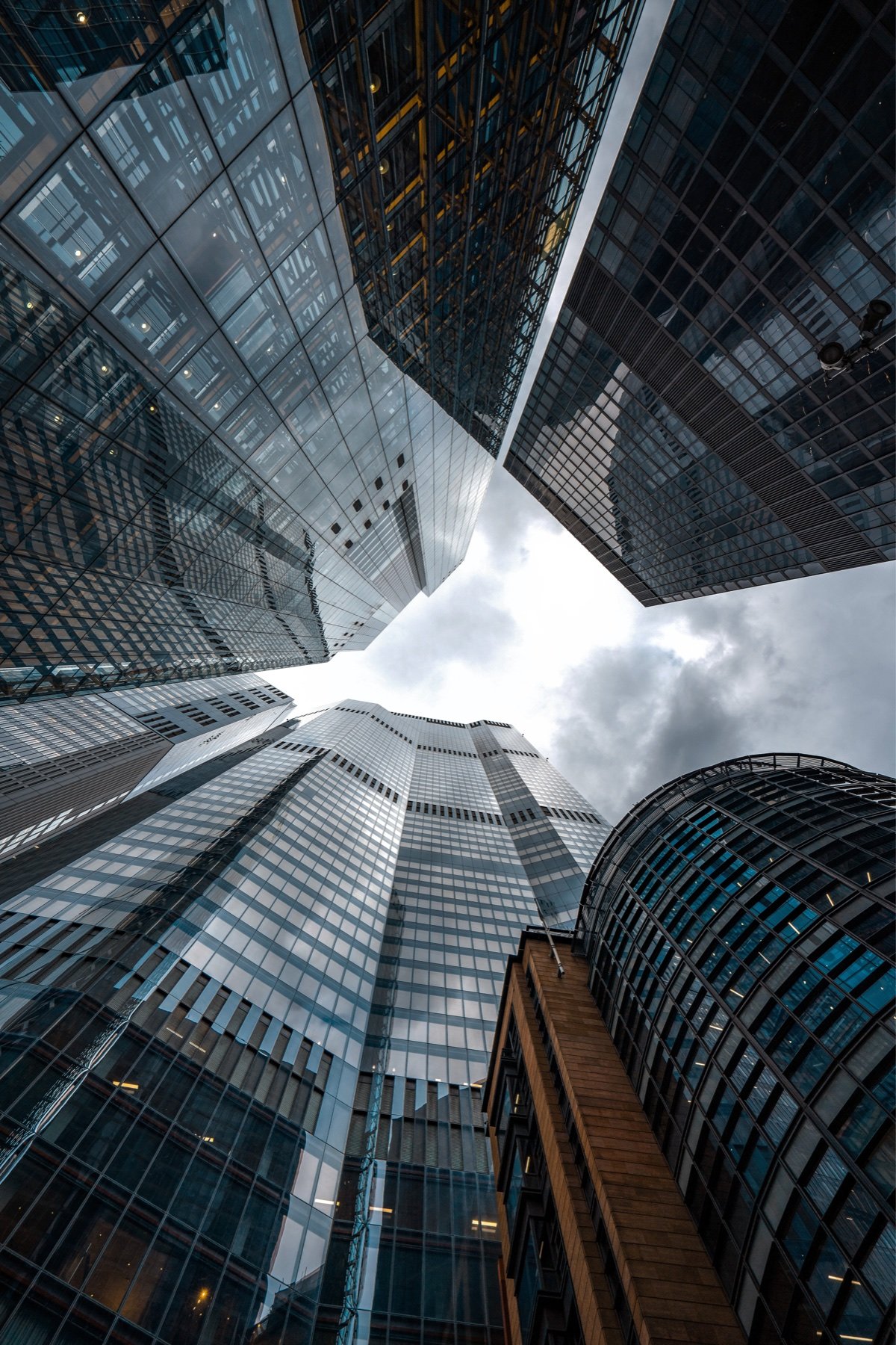 Looking upwards between glass skyscrapers towards an open sky.